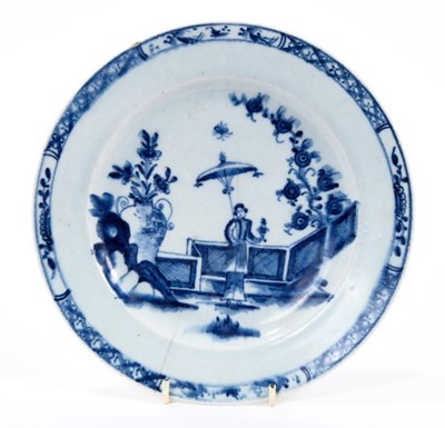Lot 28 - Lowestoft plate, painted in blue with a Chinese lady by a zig-zag fence and a large vase of flowers, with a diaper and half-flowerhead border, 22.3cm diameter