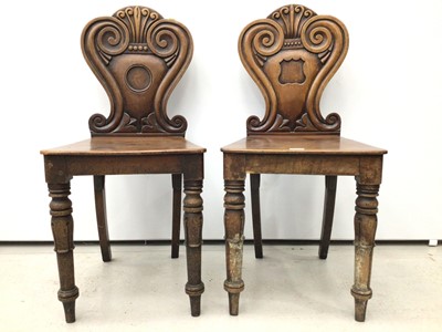 Lot 100 - Pair of Regency mahogany hall chairs with scroll backs, one with circular vacant cartouche, the other with shield shape cartouche, both with solid seats on turned legs with inverted tulip head desi...