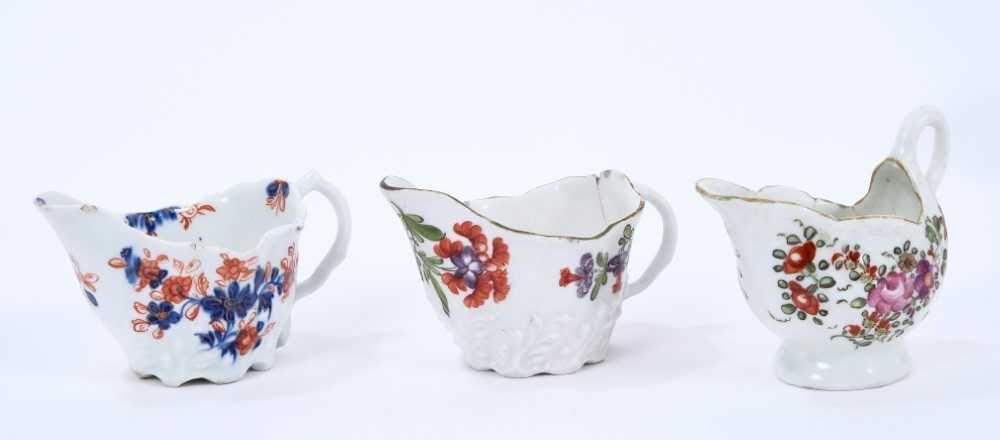 Lot 66 - Three Lowestoft cream jugs, the first of Low Chelsea ewer form, painted in 'Tulip Painter' style, 10.2cm wide, the second of the same form a painted in underglaze blue and red with floral sprays pi...