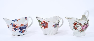 Lot 66 - Three Lowestoft cream jugs, the first of Low Chelsea ewer form, painted in 'Tulip Painter' style, 10.2cm wide, the second of the same form a painted in underglaze blue and red with floral sprays pi...
