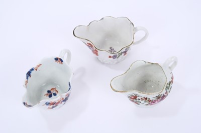 Lot 66 - Three Lowestoft cream jugs, the first of Low Chelsea ewer form, painted in 'Tulip Painter' style, 10.2cm wide, the second of the same form a painted in underglaze blue and red with floral sprays pi...