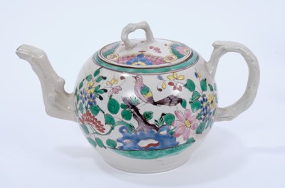 Lot 95 - Staffordshire salt-glazed teapot, c.1750, brightly enamelled on both sides with a tropical bird perched on rockwork, the cover with alternating patterned panels, with crabstock handle, spout and kn...