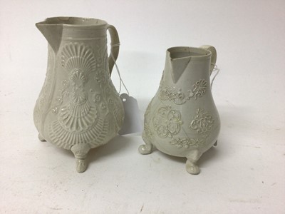 Lot 96 - Two Staffordshire white salt-glazed jugs, c.1750, both with relief moulded decoration and raised on three feet, 10.5cm and 13cm high