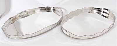 Lot 413 - Near pair of large Edwardian silver plated gallery trays of oval form with pierced gallery and gadrooned borders, raised on bun feet, each stamped 'silver on copper', each 61cm in length (2)