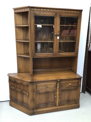 Lot 103 - Ercol lounge unit to include two height bookcase with glazed doors above enclosing two adjustable shelves with two drawers and cupboard doors below, corner unit with three fixed shelves above and s...