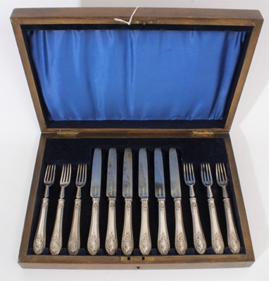 Lot 377 - Set of six Edwardian silver desert knives with silver handles with raised scroll decoration, together with matching forks (Birmingham & Sheffield 1904), in velvet lined oak case, knives 21cm in len...