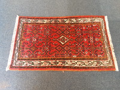 Lot 1066 - Eastern rug with geometric decoration on red ground, 120cm x 77cm