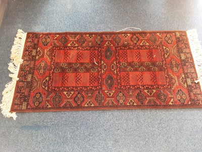Lot 1075 - Eastern rug with geometric decoration on red ground, 138cm x 67cm