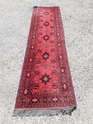 Lot 1078 - Eastern runner with geometric decoration on red ground, 297cm x 79cm