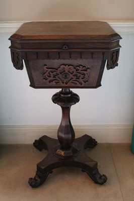 Lot 1373 - Early Victorian rosewood teapoy with canted rectangular top over a lappet carved frieze and fret carved panel, on faceted baluster column and quatrefoil base, raised on scroll feet and castors, 46c...
