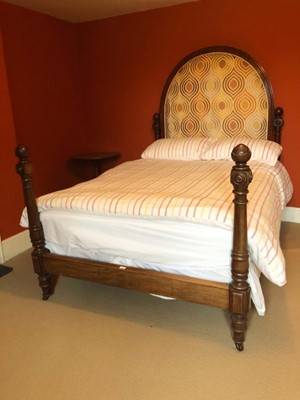 Lot 1429 - Victorian mahogany framed double bedstead, the upholstered arched headboard flanked by carved and turned pillars, matching pillars at the footboard, metal side rails and base, 210cm long x 143cm wi...
