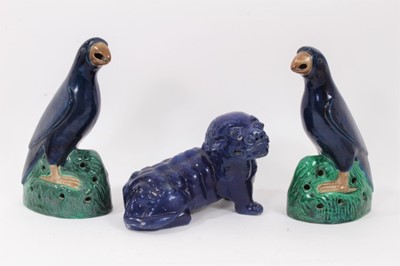 Lot 105 - Pair of Chinese blue-glazed pottery parrots, late Qing period, modelled on naturalistic green bases, 22cm and 22.5cm high, together with a Chinese blue-glazed model of a foo dog (3)