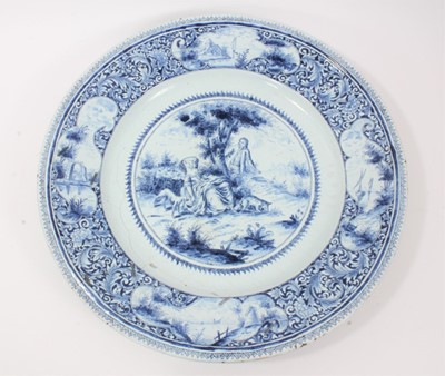 Lot 139 - 19th century Dutch blue and white Delft charger, painted with a figural scene, the edge with landscape reserves on a foliate patterned ground, 'AK' monogram to reverse, 47cm diameter