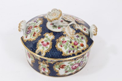 Lot 225 - Worcester butter tub and cover, c.1770, polychrome decorated with flowers within gilt scrollwork cartouches, on a blue scale ground, the cover with flower finial, 10.5cm diameter