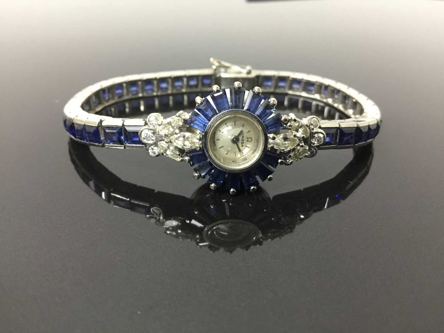 Lot 533 - 1950s/1960s ladies Omega diamond and sapphire cocktail wristwatch, the circular dial with concealed winding crown, tapered baguette cut sapphires and diamond lugs with marquise and brilliant cut di...