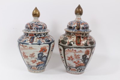 Lot 254 - Near pair of Japanese Edo period Imari vases and covers, decorated with landscapes and flowers, 26.5cm and 28cm high