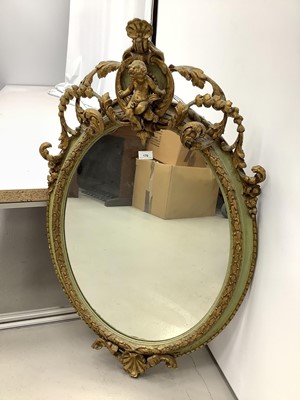Lot 170 - Oval wall mirror in green and gilt frame with cherub mount, 100cm x 61cm