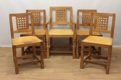 Lot 1297 - Set of five Robert Mouseman Thompson carved oak dining chairs, each with lattice carved back and close stud leather upholstery on chamfered supports with signature mouse to front leg, to include on...