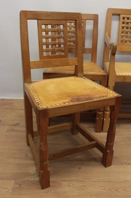 Lot 1297 - Set of five Robert Mouseman Thompson carved oak dining chairs, each with lattice carved back and close stud leather upholstery on chamfered supports with signature mouse to front leg, to include on...