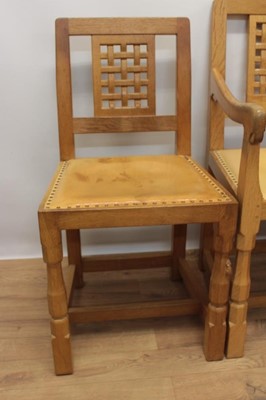 Lot 1297 - Set of five Robert Mouseman Thompson carved oak dining chairs, each with lattice carved back and close stud leather upholstery on chamfered supports with signature mouse to front leg, to include on...