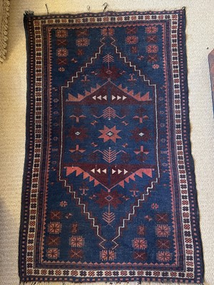 Lot 973 - An antique Eastern rug with geometric medallions on blue and red ground, 130cm x 82cm, together with another on red ground, 118cm x 88cm (2)