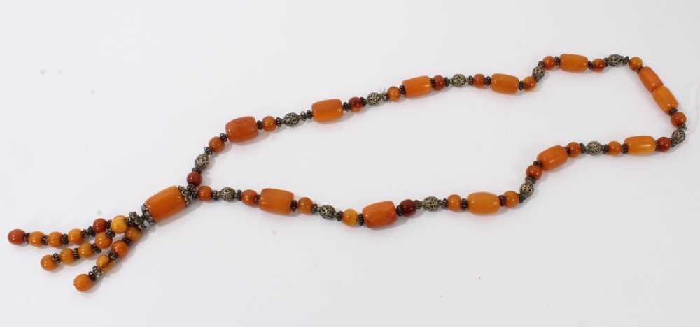 Lot 38 - Amber bead necklace with white metal spacers and tassel terminal