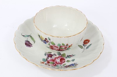 Lot 24 - Worcester fluted tea bowl and saucer, circa 1772, polychrome painted with flowers, with gilt rims, the saucer measuring 13.5cm diameter