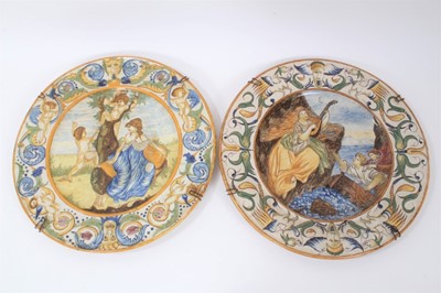 Lot 108 - Good pair of Italian maiolica dishes, probably early 20th century, decorated with classical scenes, the borders with a pattern of cherubs, masks and scrollwork motifs, 40cm diameter