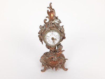 Lot 1949 - 19th century French brass mantel clock, decorated in the rococo style with a cherub, scrollwork motifs and flowers, with enamelled dial, 21.5cm high