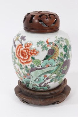 Lot 119 - Chinese famille verte porcelain jar, 18th/19th century, decorated with a tropical bird perched on rockwork, surrounded by flowers and foliage, together with carved wooden cover and stand, 13.5cm hi...