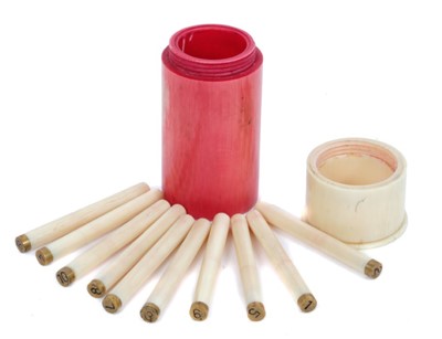Lot 919 - Late 19th / early 20th century butt marker in the form of a shotgun cartridge, with red stained ivory case and white screw on cap, containing 10 place markers. 7.5cm overall length